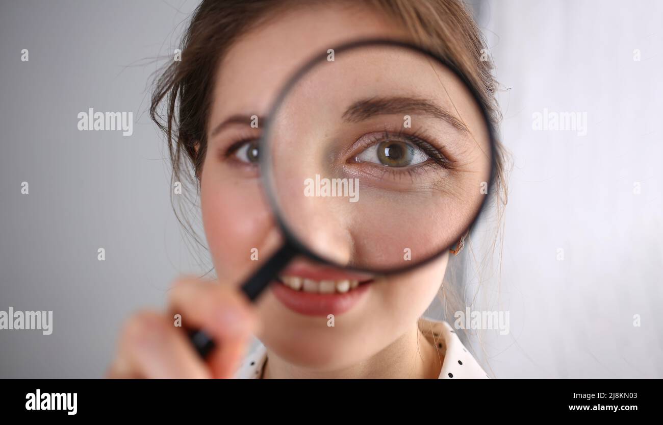 Young woman look through magnifying loupe, interested in everything Stock Photo