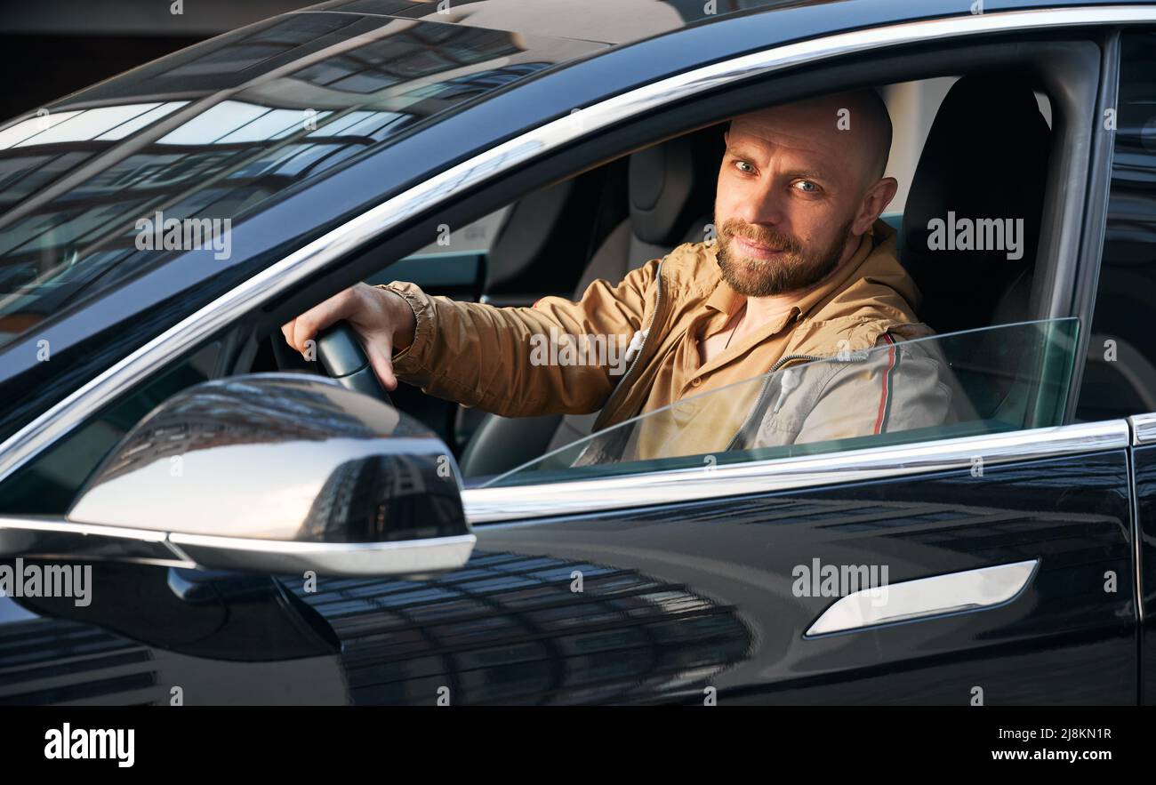 Portrait of adult male driving black car. Man with beard sitting in the ...