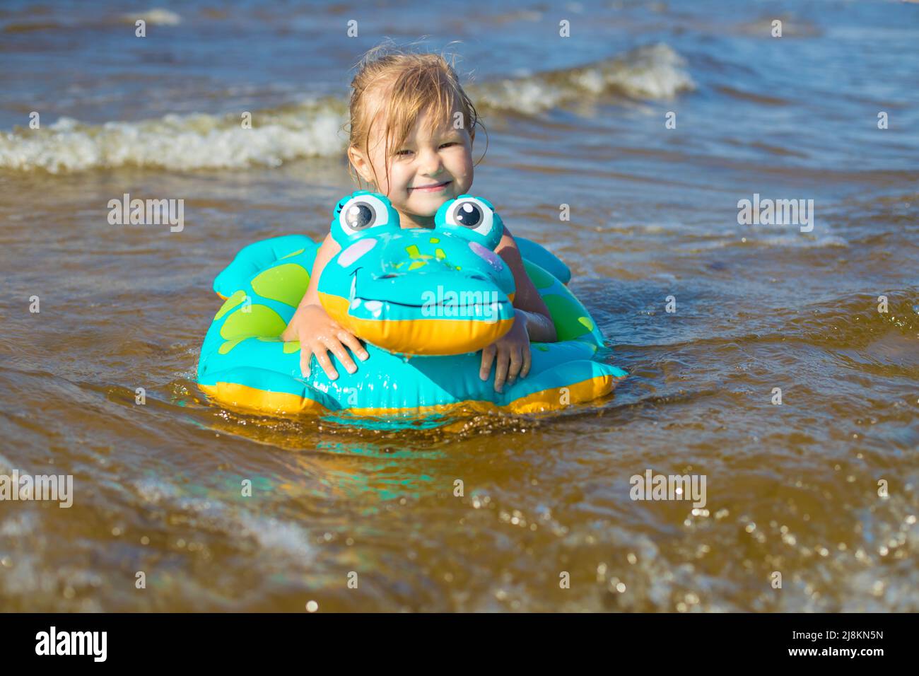 Happy girl swimming on an inflatable crocodile toy in the sea Stock
