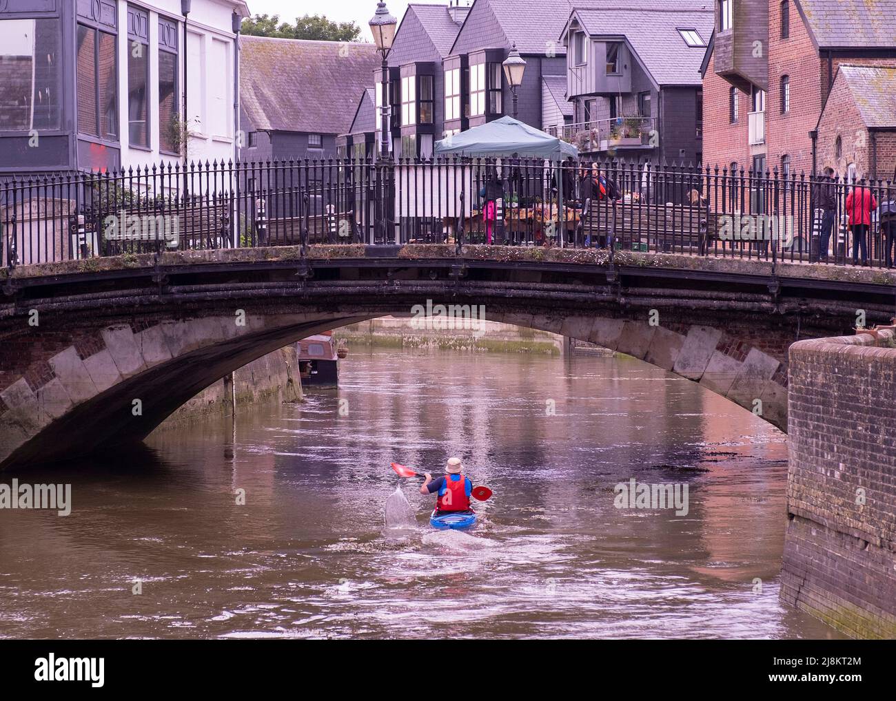 A man paddles a canoe under a busy bridge in Lewes East Sussex Stock Photo