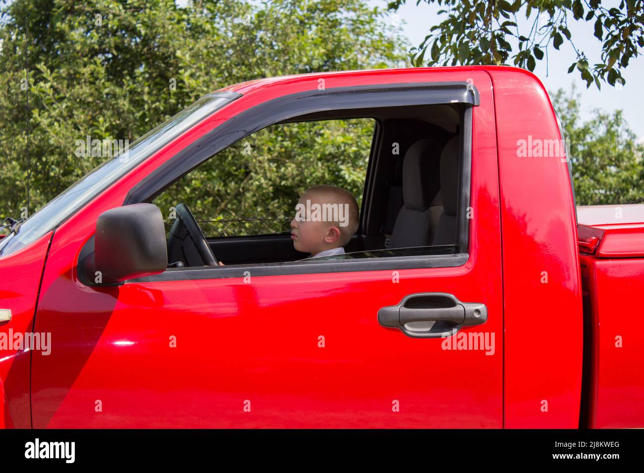 driving a red pickup truck sitting boy Stock Photo