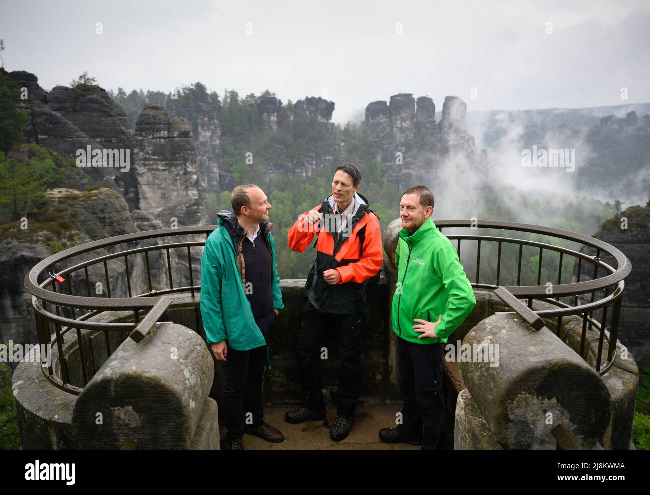 Lohmen, Germany. 17th May, 2022. Michael Kretschmer (CDU, r.), Minister President of Saxony, Wolfram Günther (Bündnis90/Die Grünen, l.), Environment Minister of Saxony, and Ulf Zimmermann, Head of the Saxon Switzerland National Park, stand on the Bastei before the start of the cabinet meeting away from home. Credit: Robert Michael/dpa/Alamy Live News Stock Photo