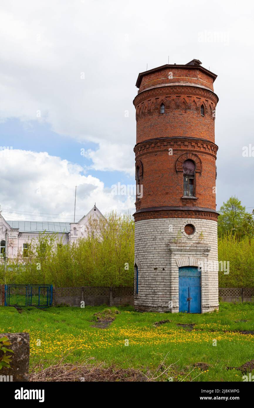 Ancient water tower made of bricks against a cloudy sky. Stock Photo