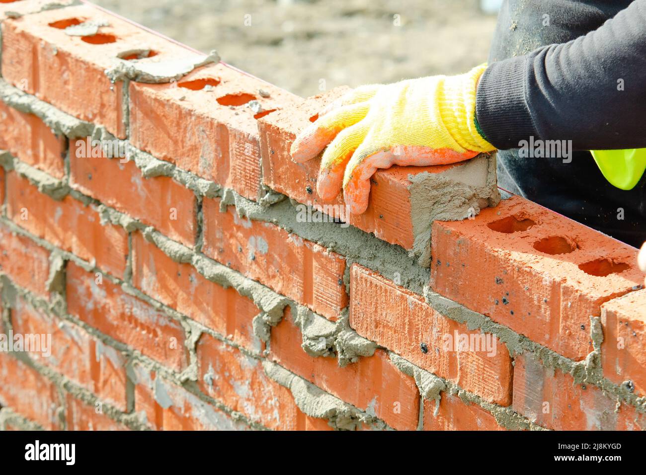 Bricklayer laying bricks on mortar on new residential house