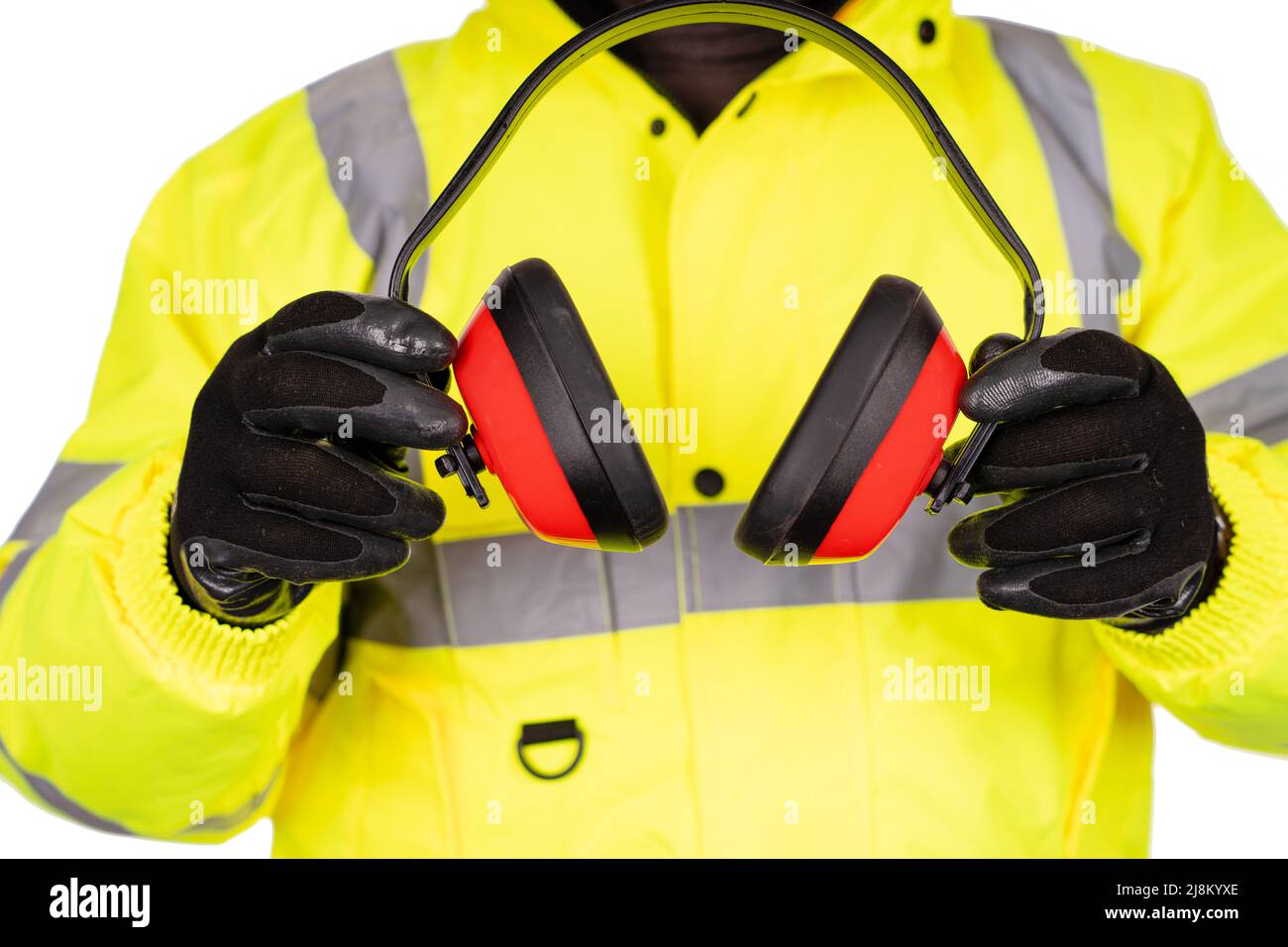 A construction worker in  yellow hi-viz coat on white background gives foam-filled padded ear defenders to the viewer. Wear hearing protection in a no Stock Photo