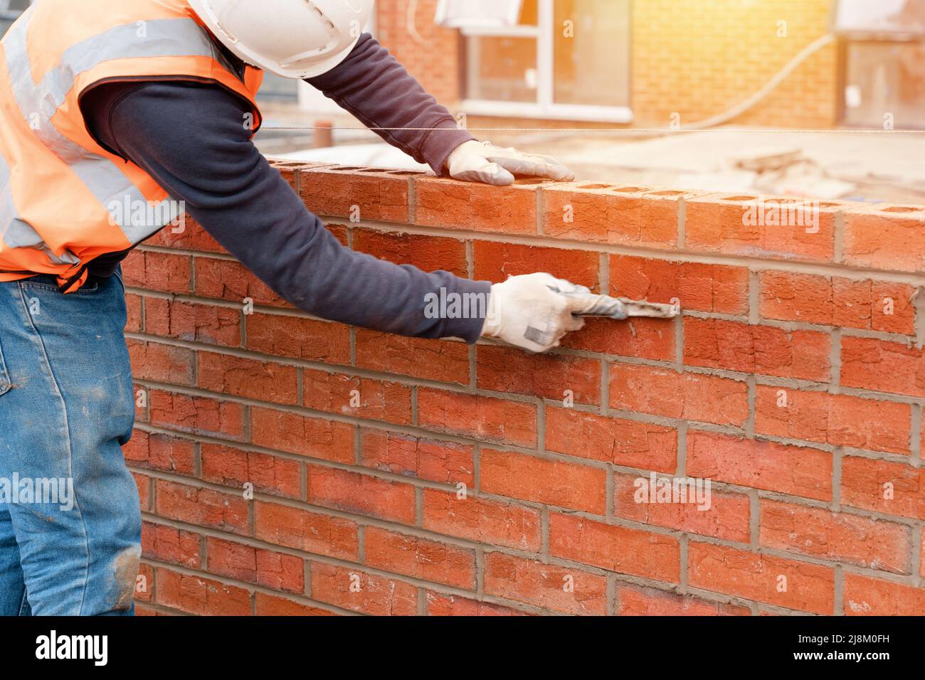 Bricklayer laying bricks on mortar on new residential house