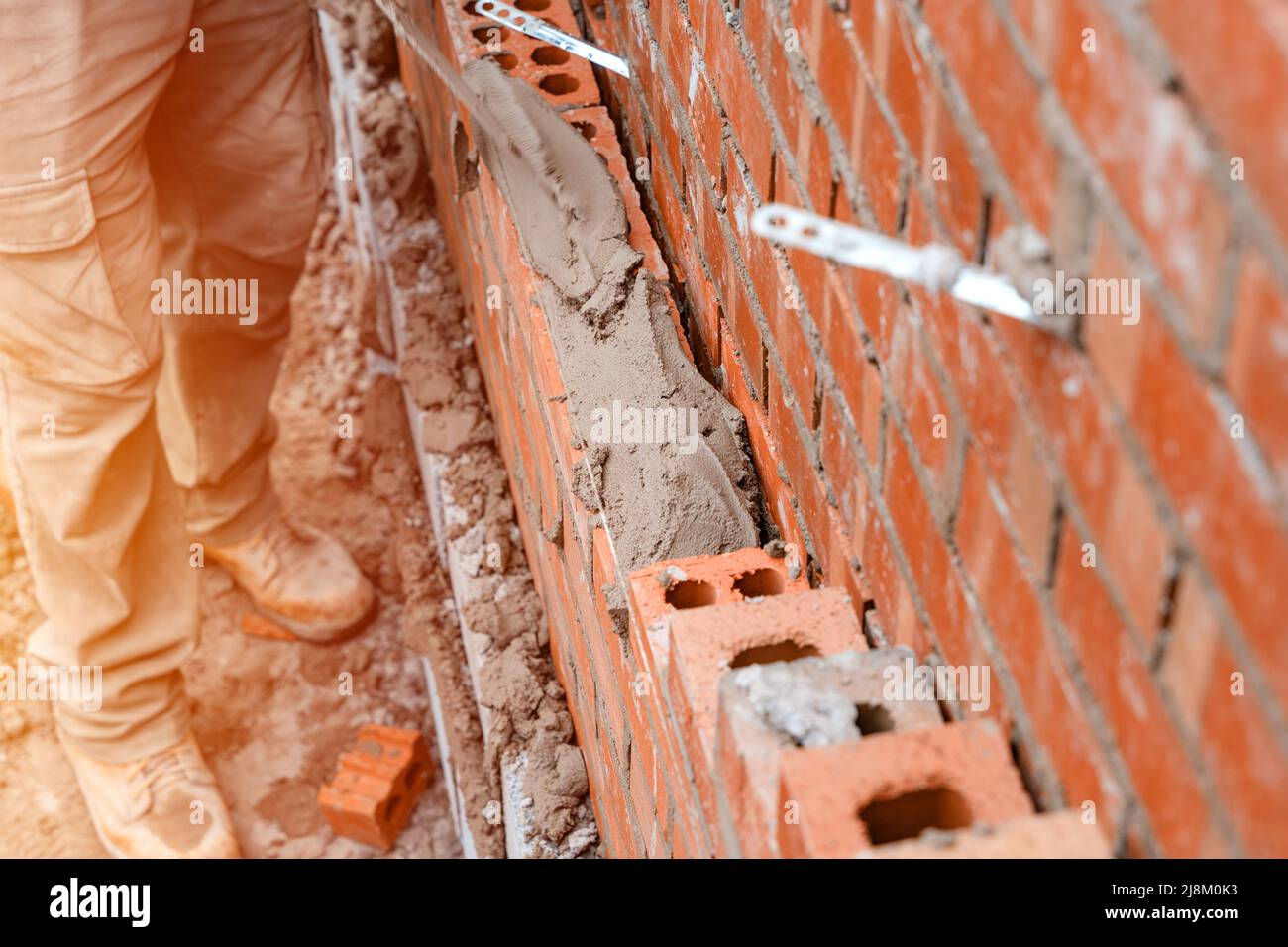 Bricklayer laying bricks on mortar on new residential house