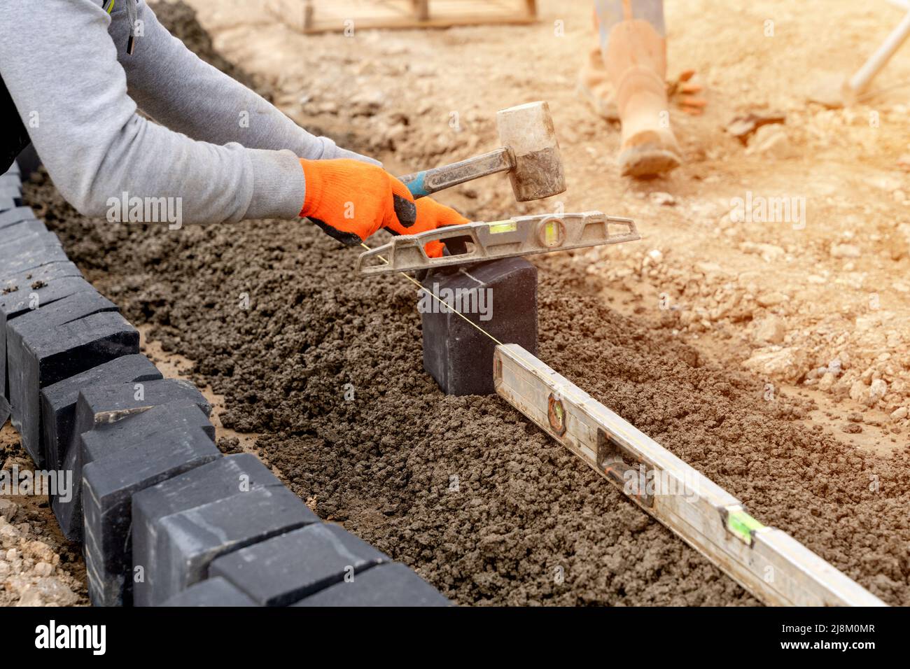 Builder installing paving blocks during road and footpath construction