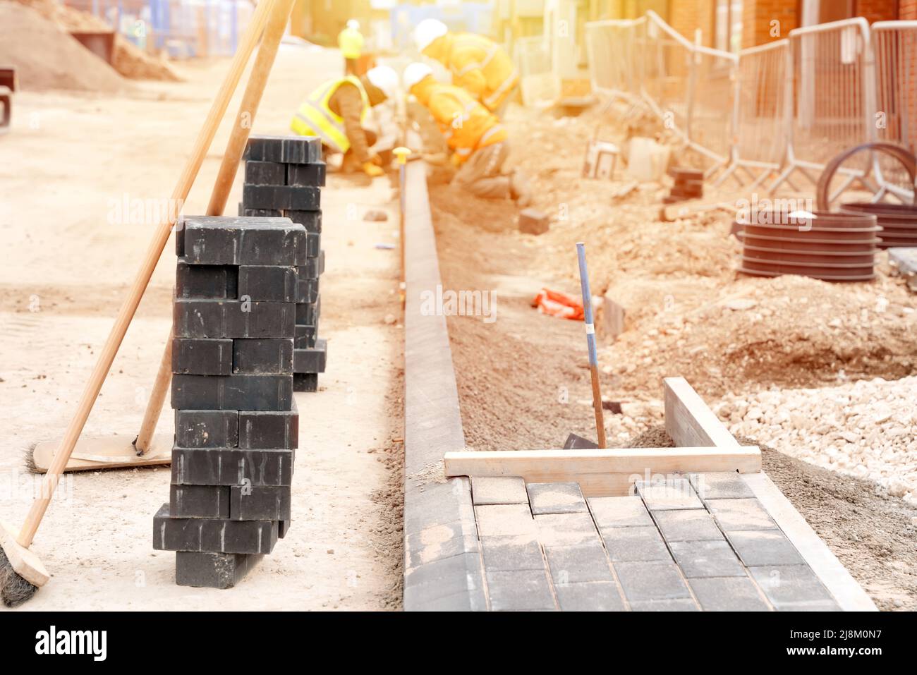 Builders installing paving blocks during road and footpath construction