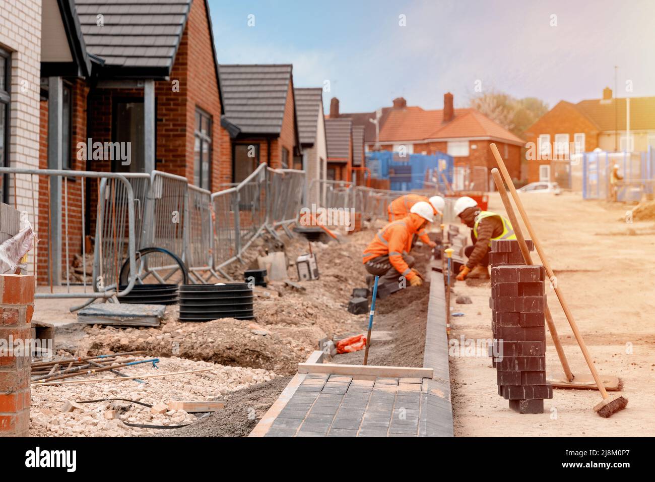 Builders installing paving blocks during road and footpath construction