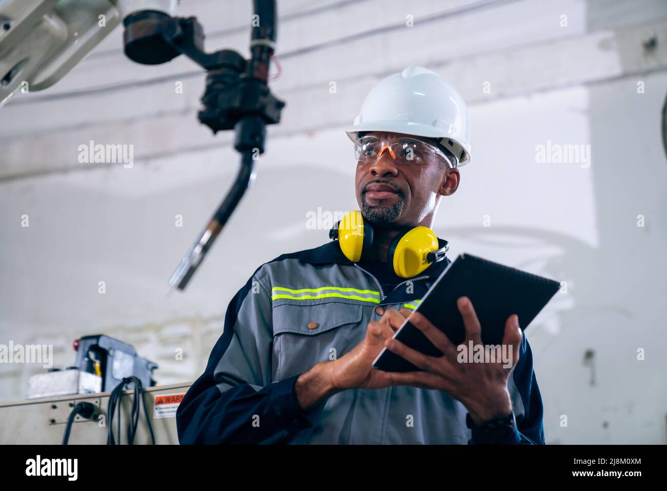 African American factory worker working with adept robotic arm in a workshop . Industry robot programming software for automated manufacturing Stock Photo