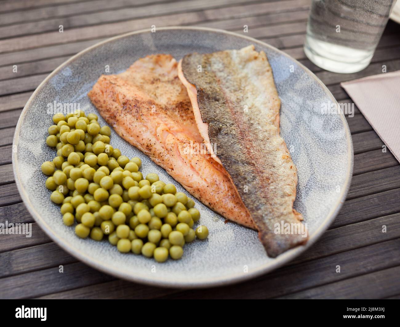 Top view of baked trout fillet served on plate with peas closeup Stock Photo