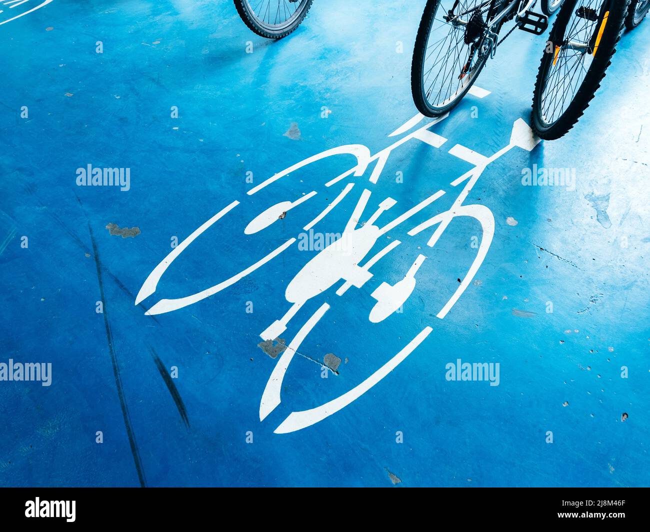 Bicycle parking area with bike pictogram symbol on ground and wheels in the background Stock Photo