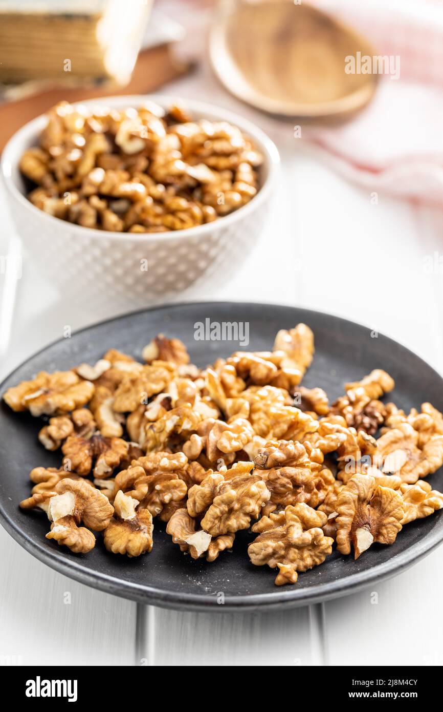 Peeled walnut kernels on plate on a white table. Stock Photo