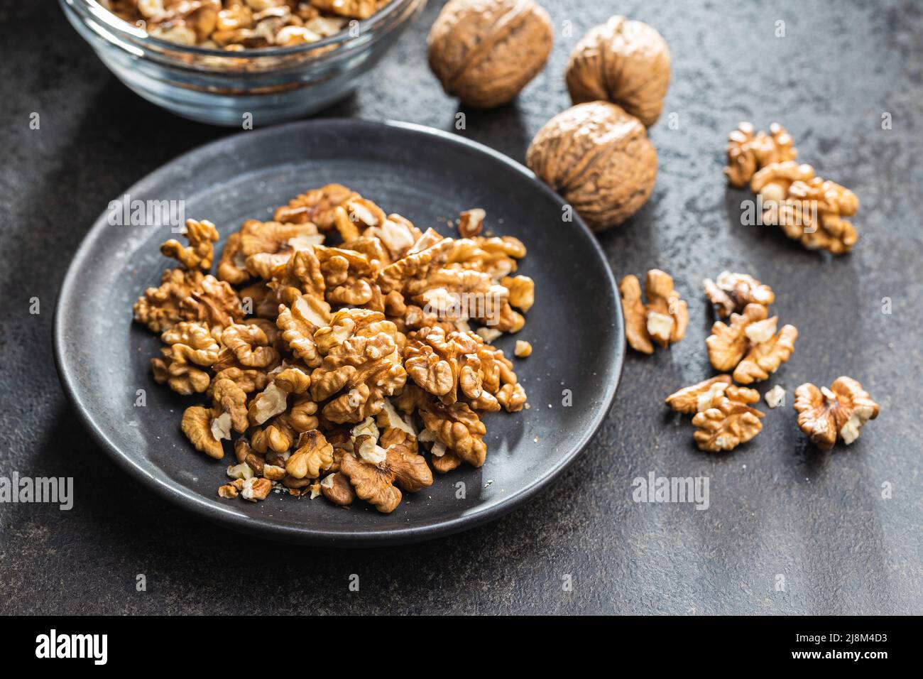 Peeled walnut kernels on plate on a black table. Stock Photo