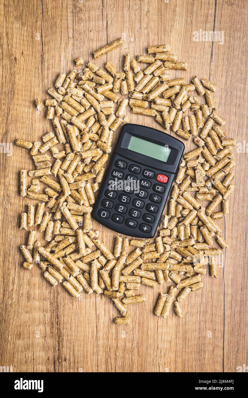 Wooden pellets, biofuel on a wooden table. Ecologic fuel made from biomass and calculator. Renewable energy source. Top view. Stock Photo