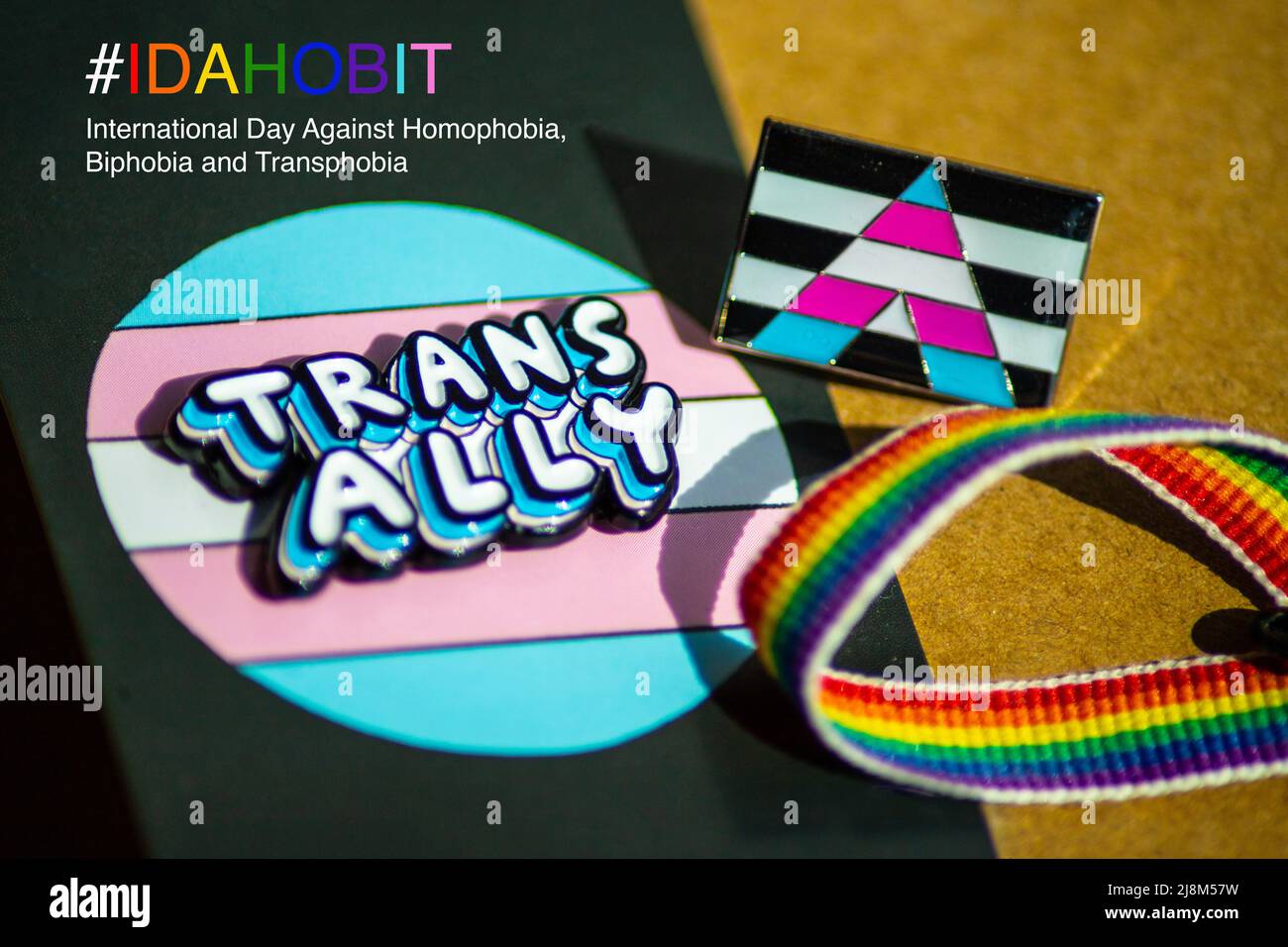Close up of 'trans ally' and trans ally flag badge with a rainbow ribbon, with International Day Against Homophobia, Biphobia and Transphobia text Stock Photo