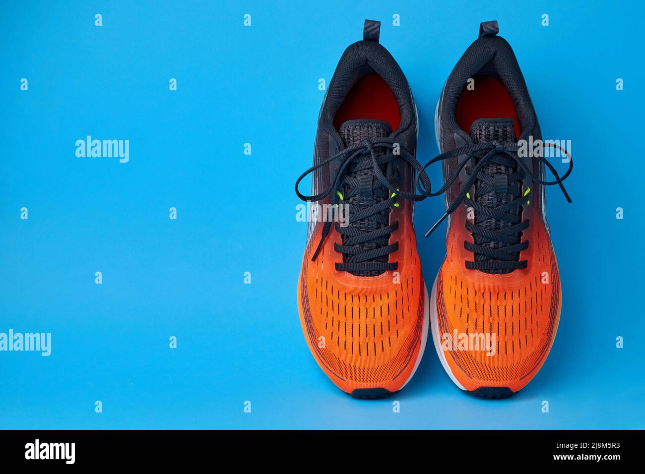 Orange sneakers on a blue background with copy space. Shoes for jogging, running, fitness, physical training Stock Photo