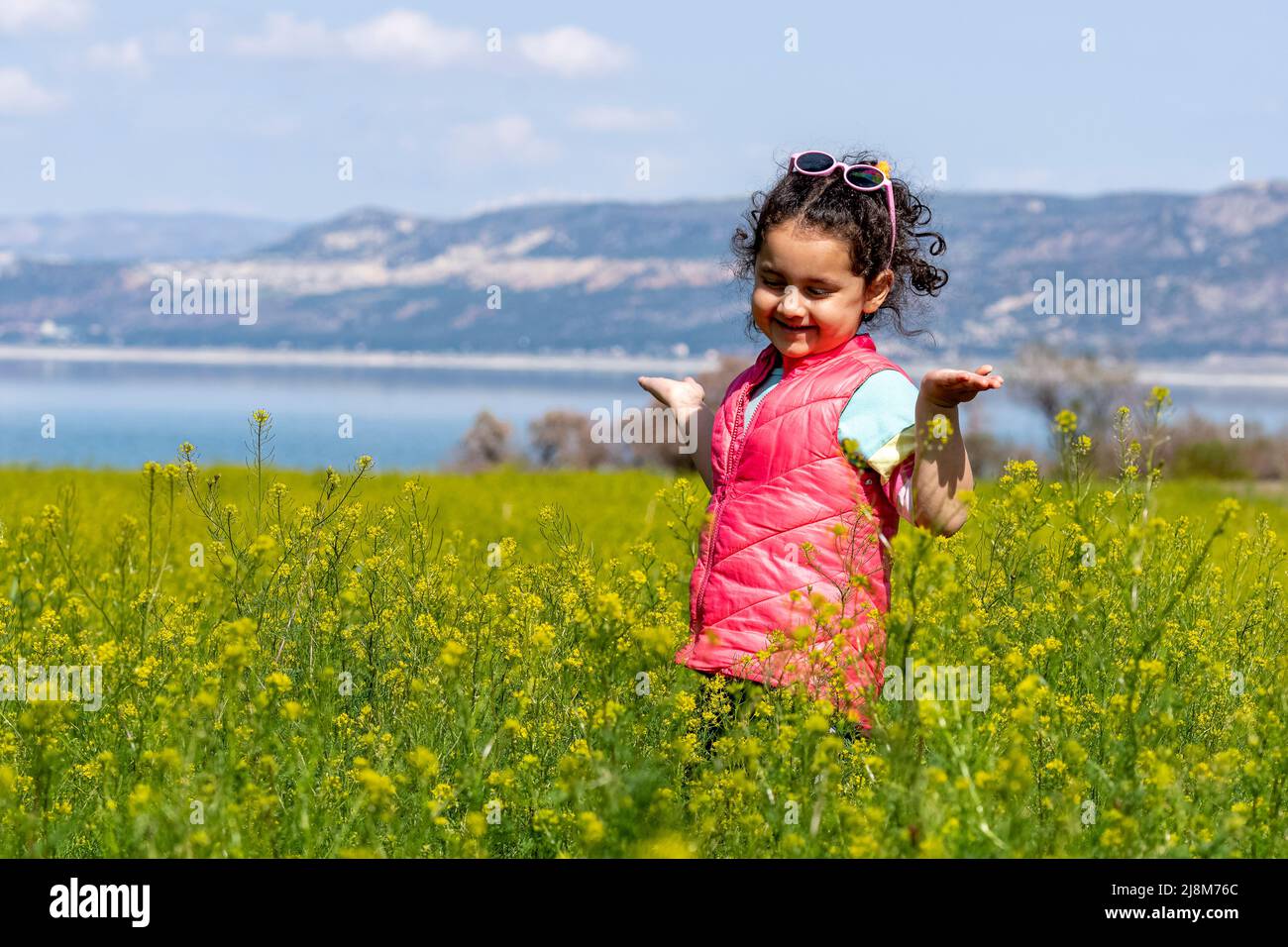 Selective focus shot of little girl in mustard field. Stock Photo