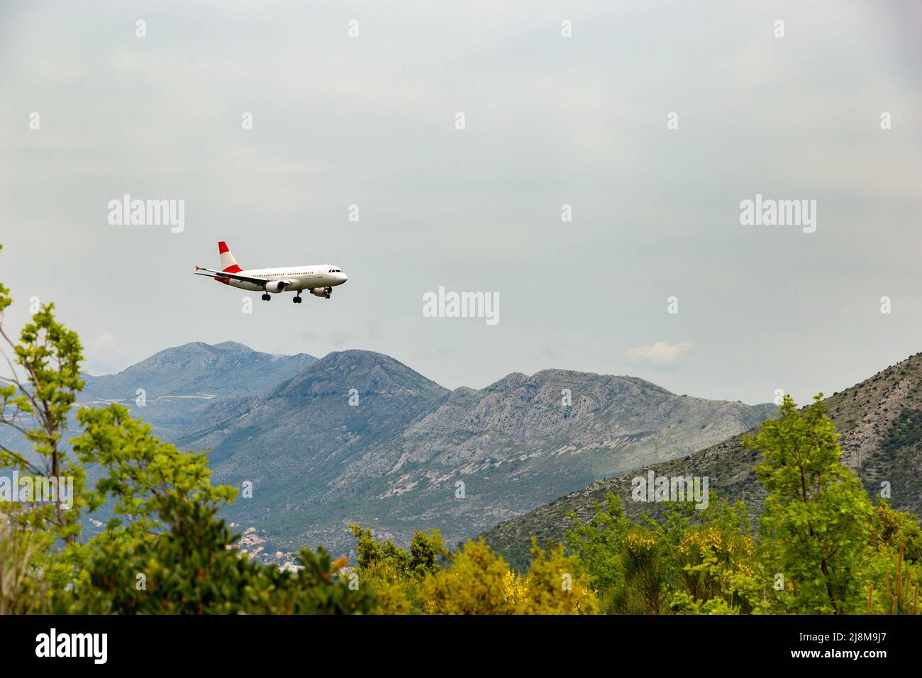 Red-white color airplane landing in Dubrovnik airport (Cavtat). Stock Photo