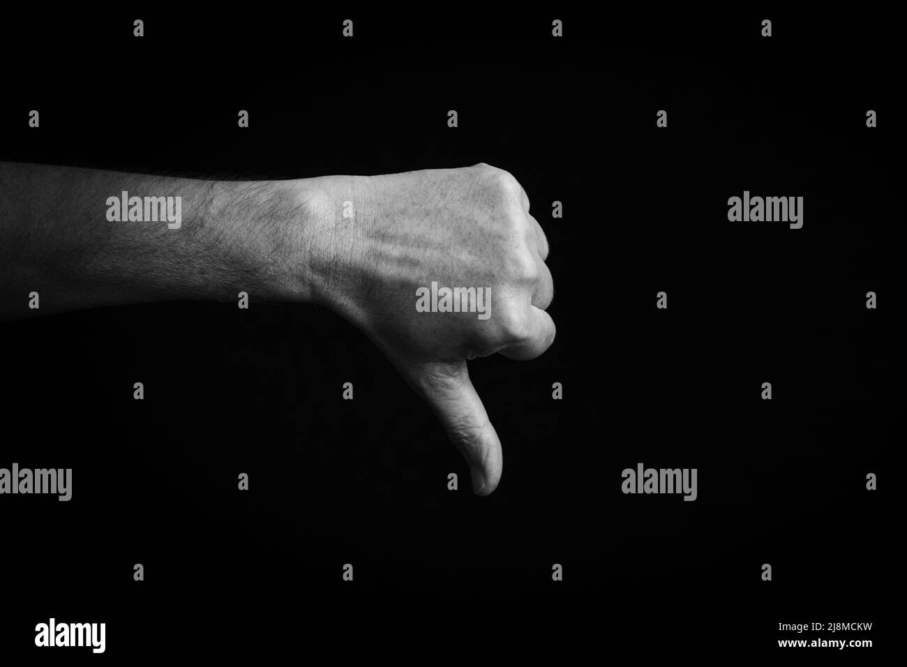 Dramatic black and white image of Thumbs Down emoji isolated on black background Stock Photo