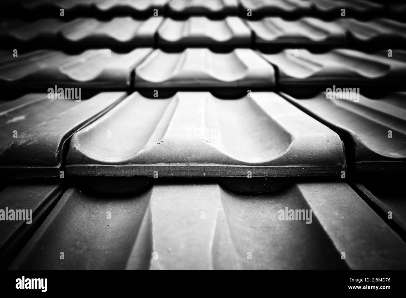 Close up, low angle view of wave shaped ranged top roof-tiles. Monochrome abstract architectural background texture. Stock Photo