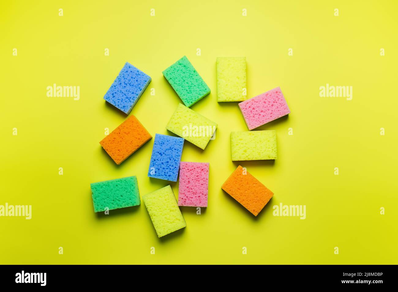 plenty of bright multicolored sponges on yellow background, top view Stock Photo