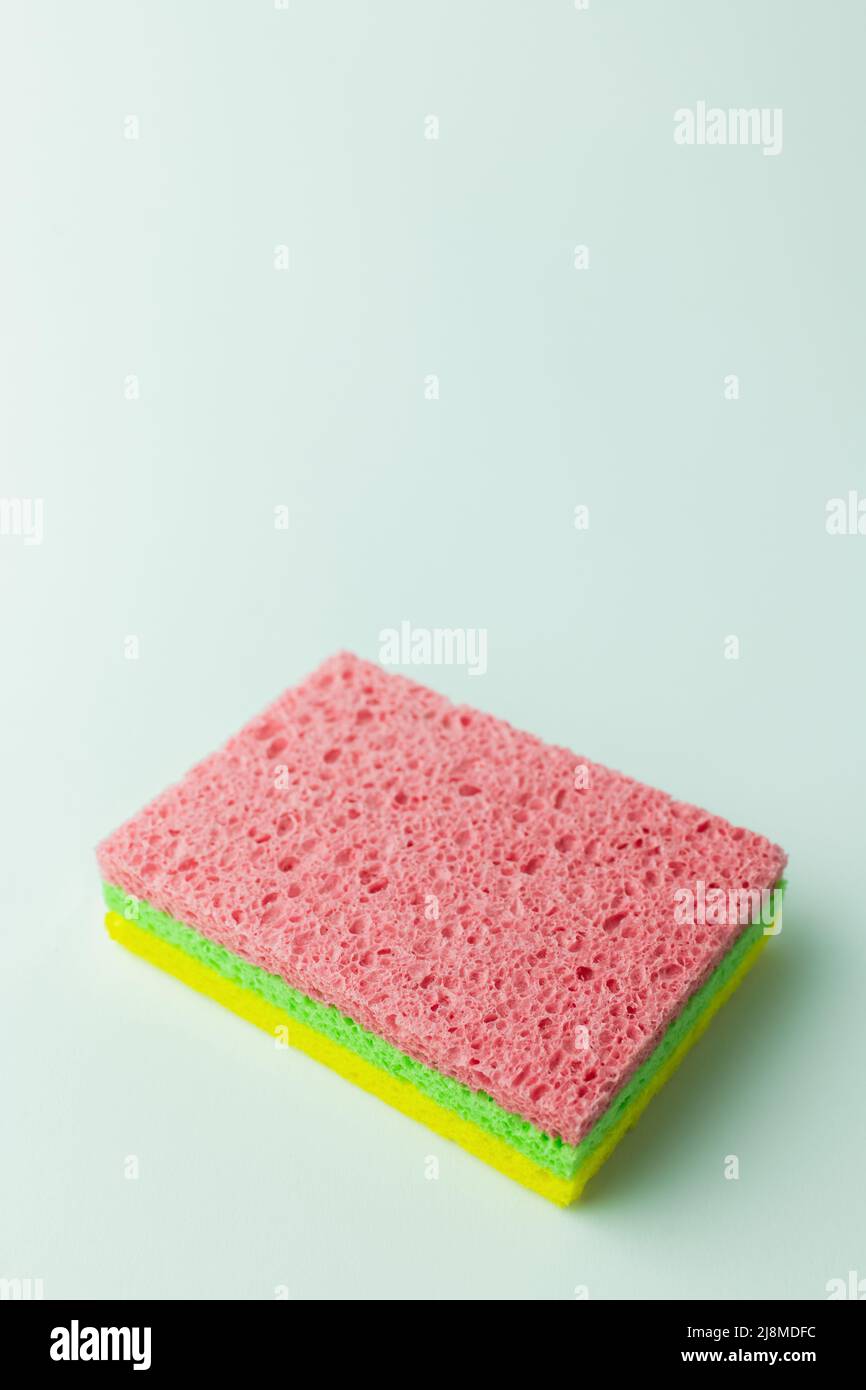 porous pink, green and yellow sponge rugs on grey background with copy ...