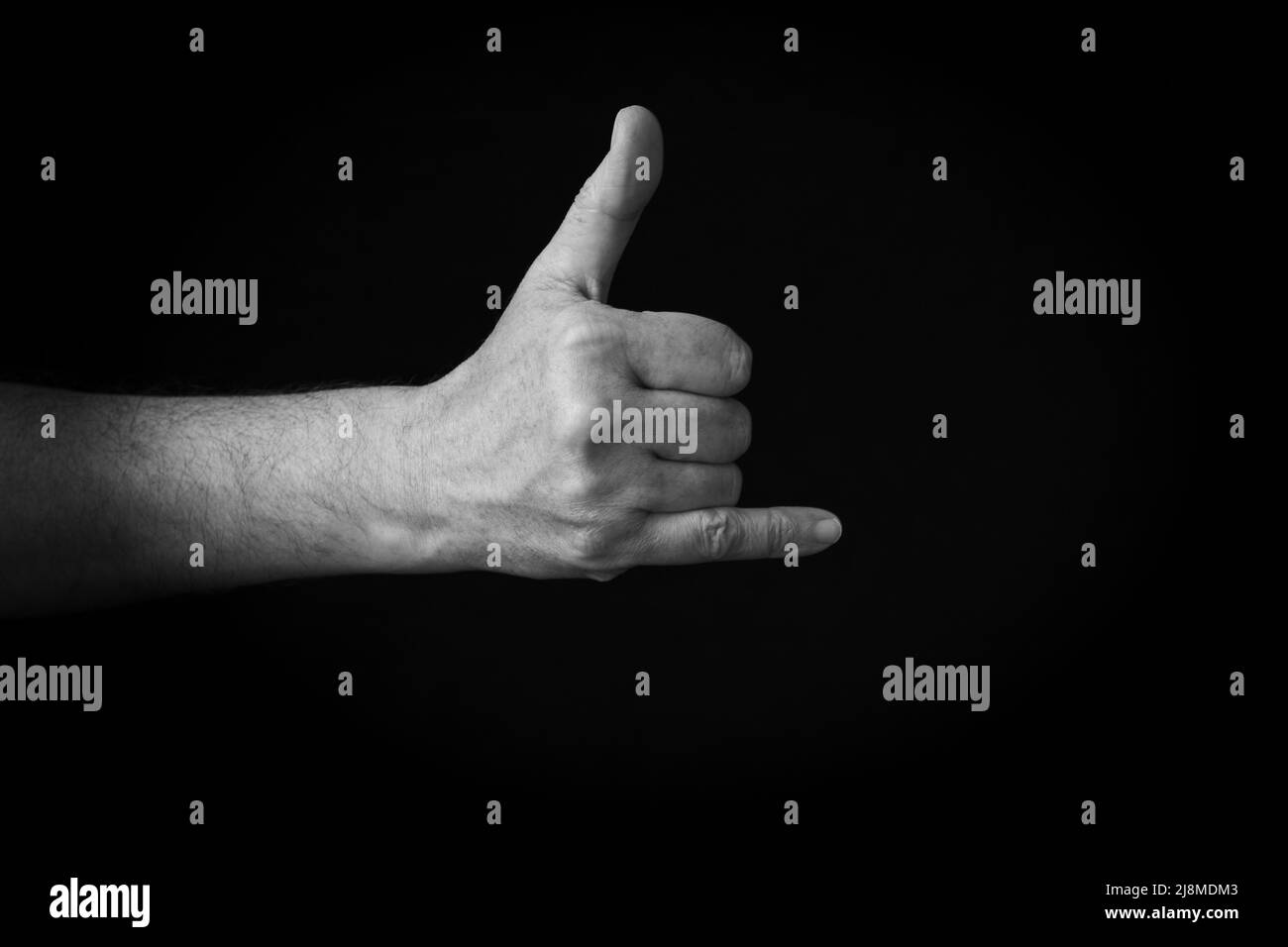 Dramatic black and white image of Call Me Hand emoji isolated on black background Stock Photo