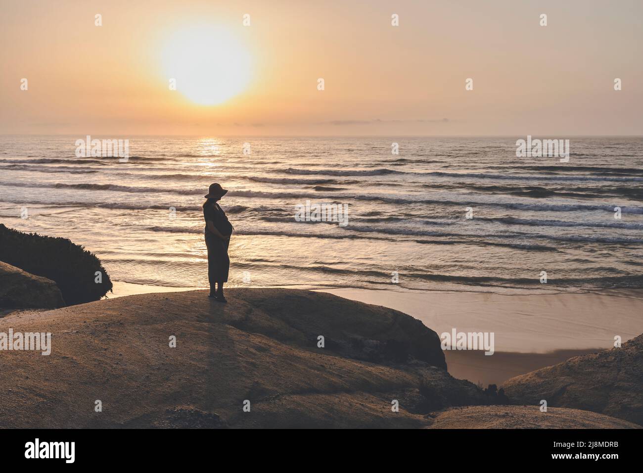Pregnant woman on the beach at sunset  enjoying the view Stock Photo