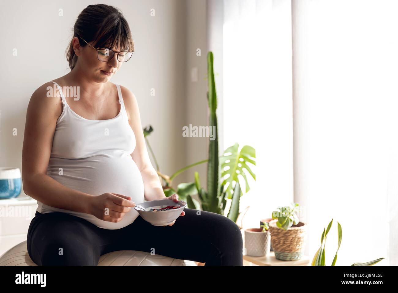 Pregnant woman working at home resting and eating healthy food Stock Photo