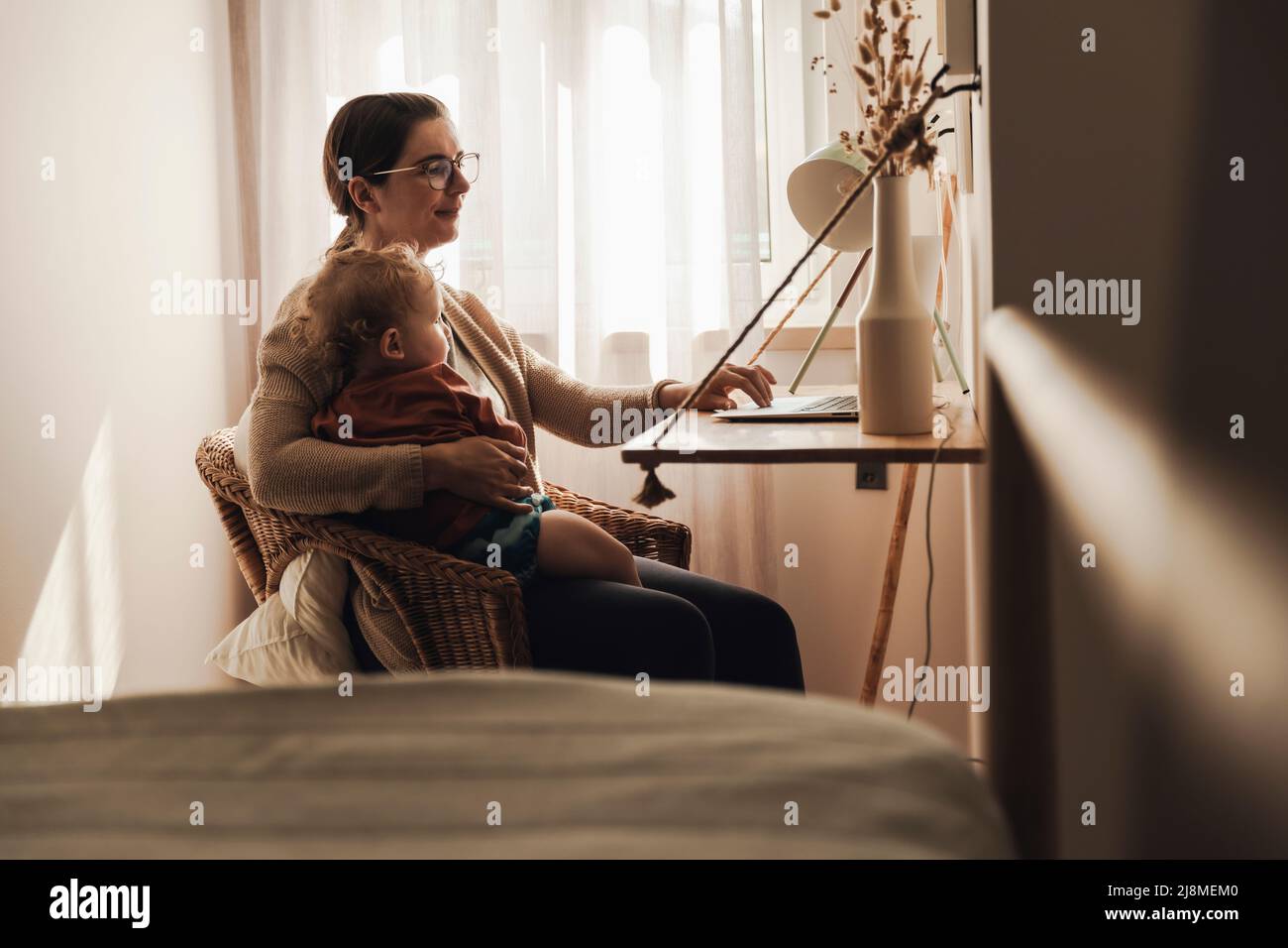 Busy woman working at home with a baby in the lap Stock Photo