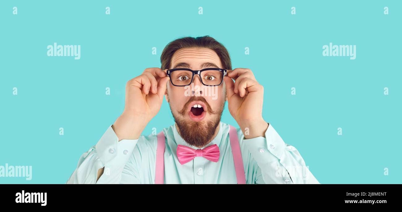 Nerdy man in glasses, shirt and bow tie looking at camera with funny surprised face expression Stock Photo