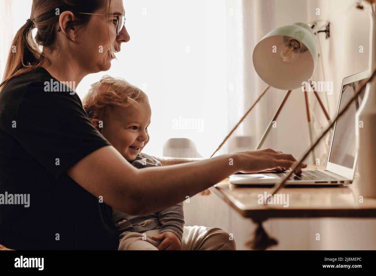 Busy woman working at home with a baby in the lap Stock Photo