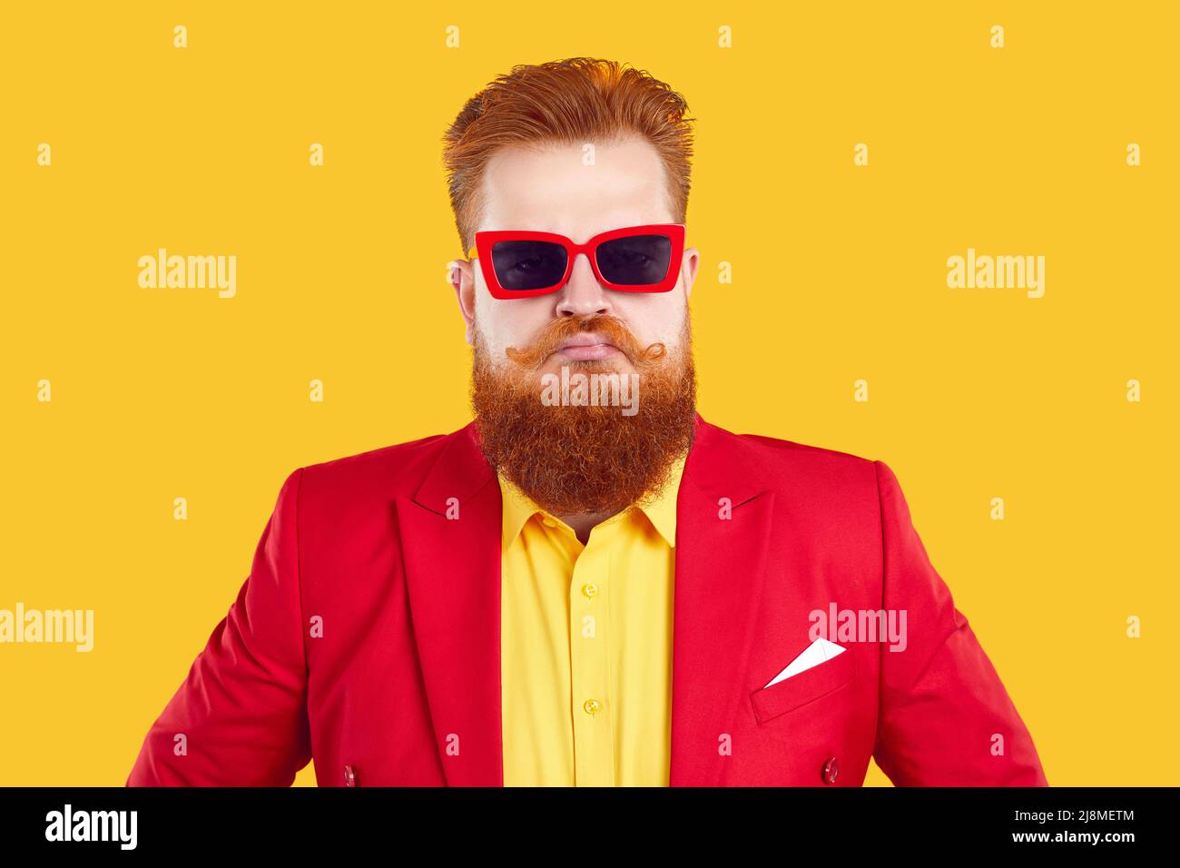 Funny stylish extravagant bearded chubby man pretending to be serious on vivid yellow background. Stock Photo
