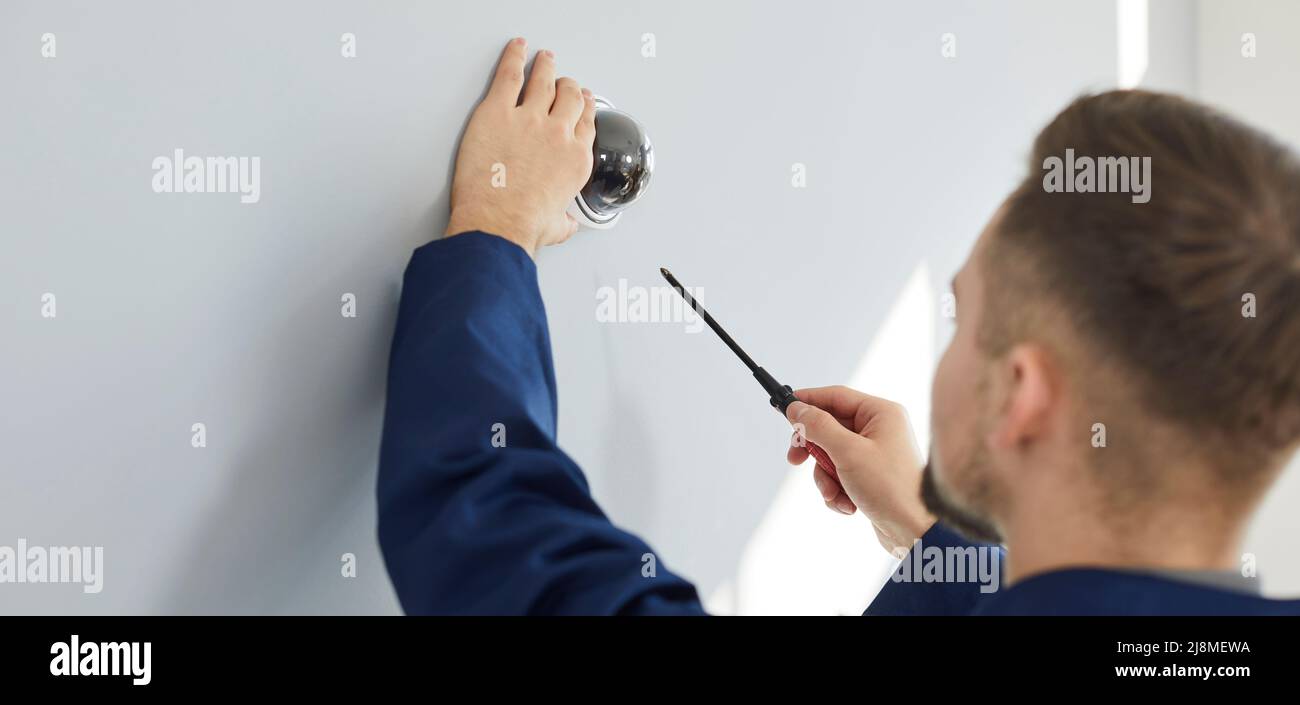 Electrician installing a surveillance CCTV dome camera on a wall in the