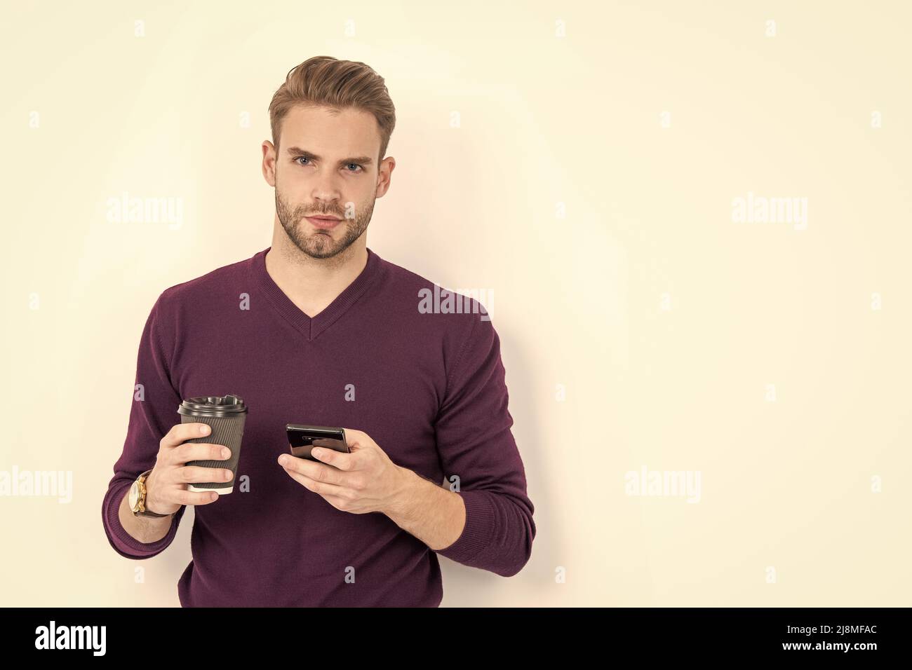 Caffeine and smartphone addiction. Handsome man use phone drinking coffee. Addiction to technology Stock Photo