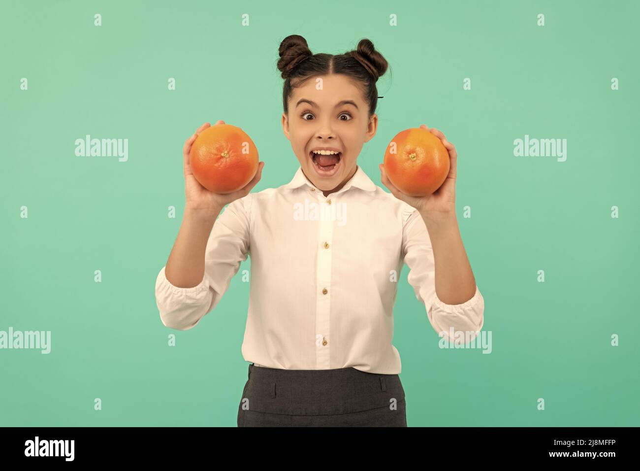 cheerful teen girl wear uniform holding grapefruit on blue background, vitamin Stock Photo