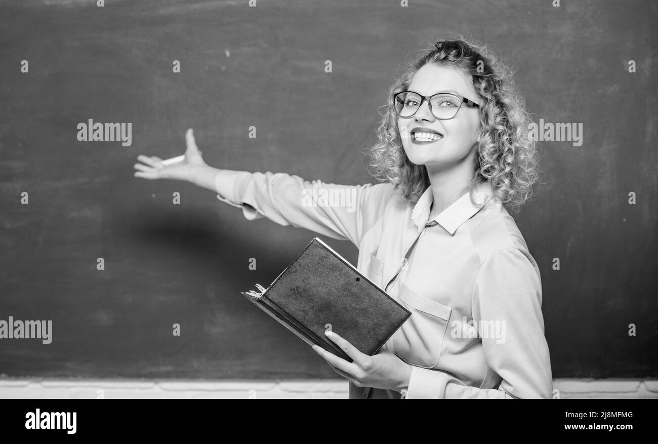 Pedagogue hold book and explaining information. Teacher explain hard topic. Woman school teacher in front of chalkboard. Teacher best friend of Stock Photo