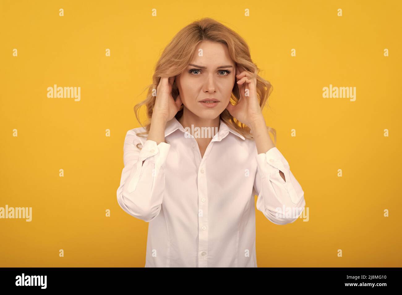 Unhappy ill woman touch ears suffering from ear pain yellow background, earache Stock Photo