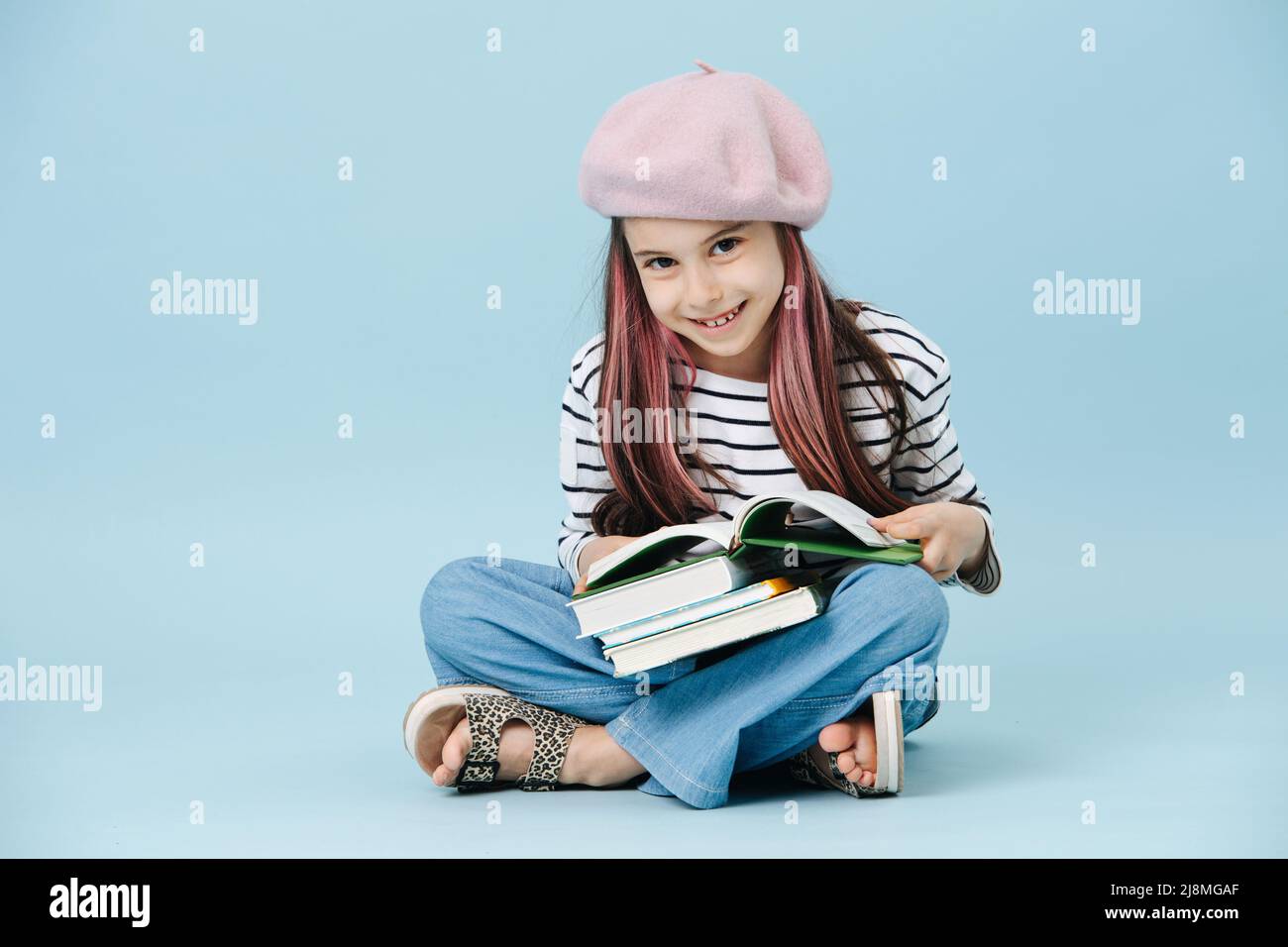 Pretty smiling tween girl in french beret sitting crosslegged with