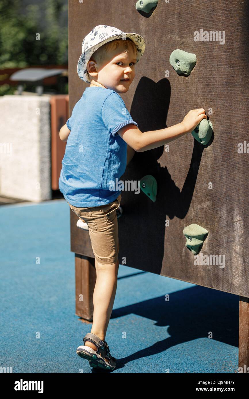 A young mountaineer trains to climb the climbing wall. Active child time spending concept image. Stock Photo