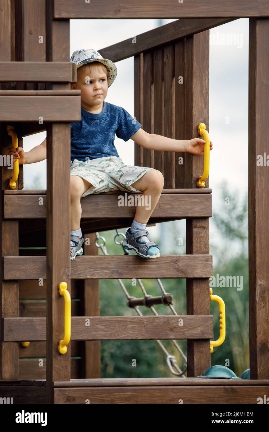 A cute little brave boy at the top of the playground. The child looks away in to distance Stock Photo