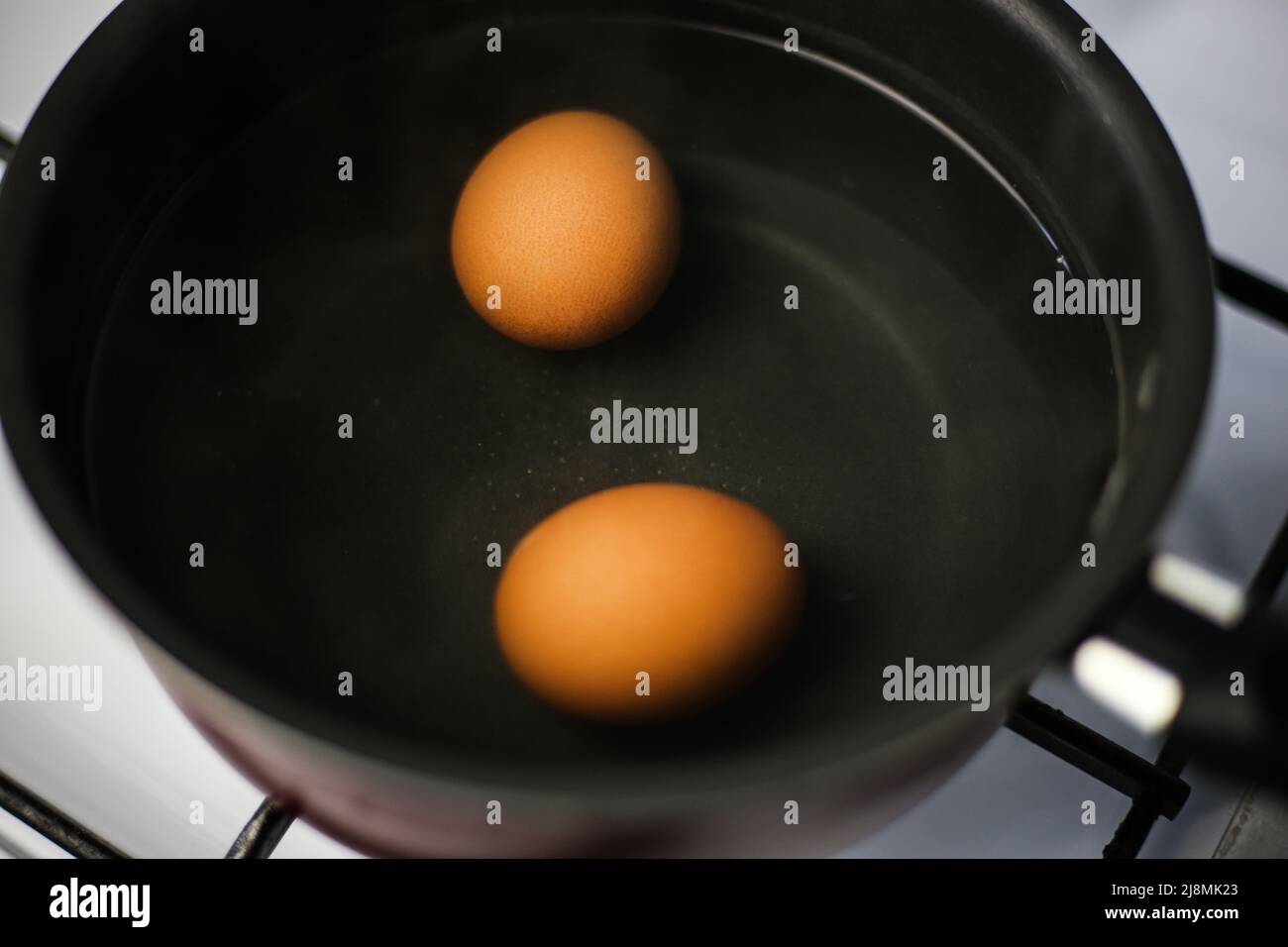 Two boiled brown eggs in a pot of boiling water Stock Photo Alamy