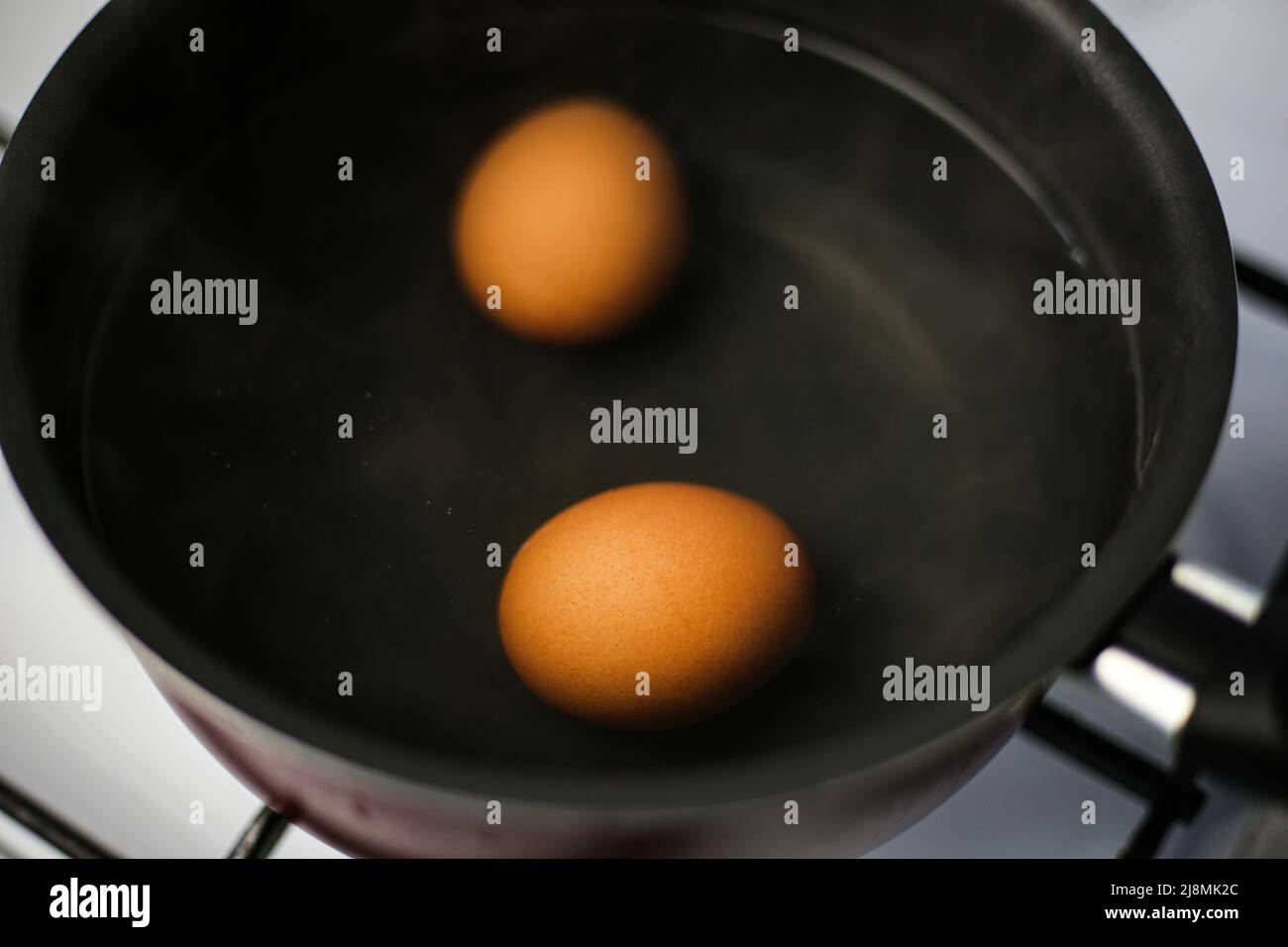 Two boiled brown eggs in a pot of boiling water Stock Photo Alamy