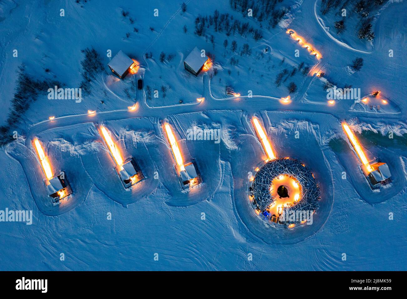 Aerial view of the illuminated Arctic Bath Hotel made with timber in the snowy landscape at dusk, Harads, Lapland, Sweden Stock Photo