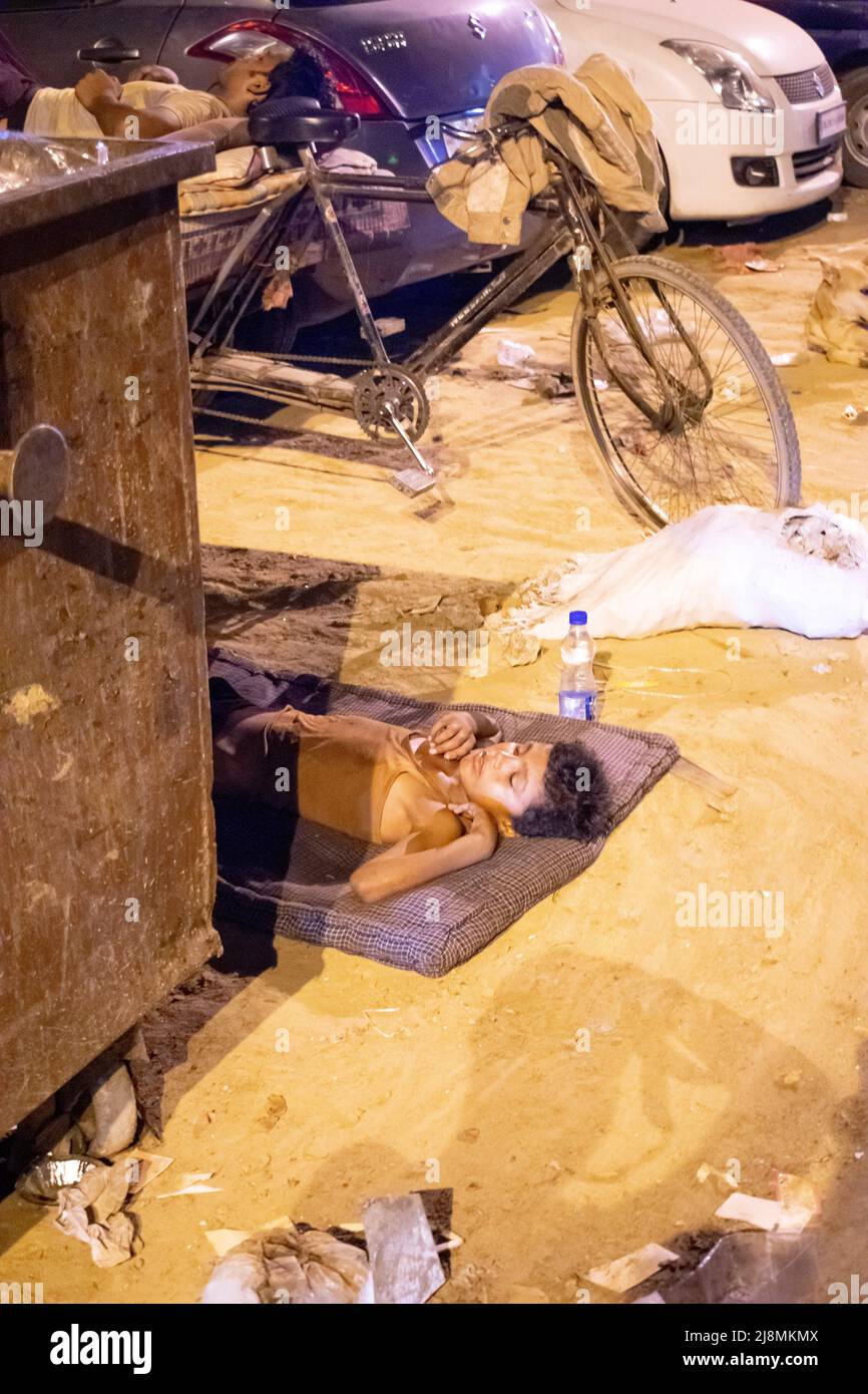 A homeless poor orphan boy is sleeping near the waste bin Stock Photo