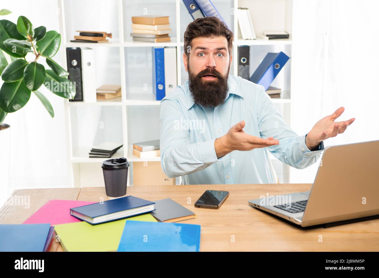 Indignant man complaining while working at work computer in office, indignation. Stock Photo