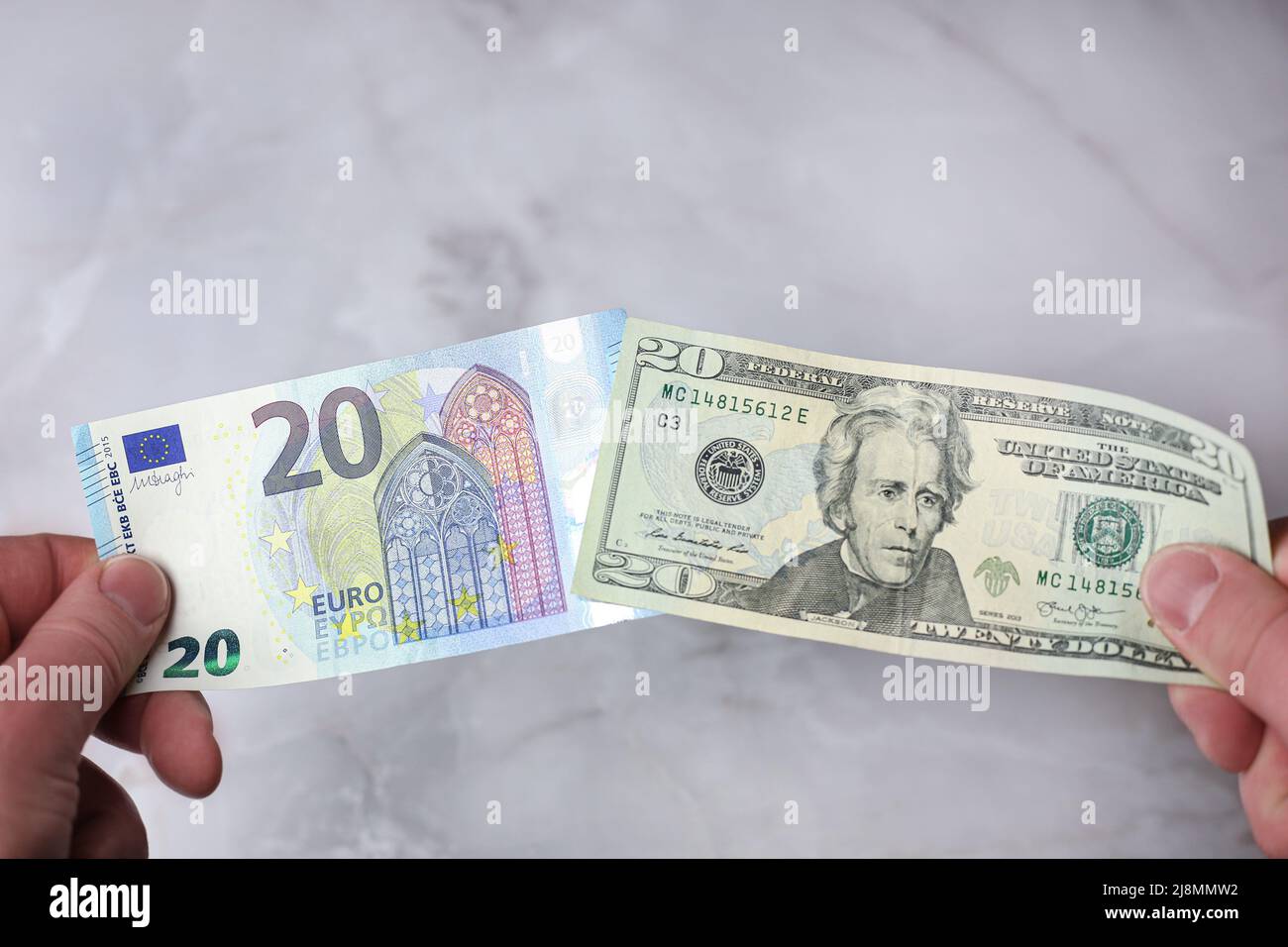 Banknotes of 20 euros and 20 US dollars in hands for comparison Stock Photo