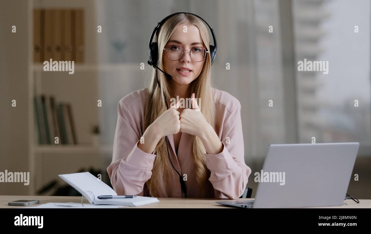 Woman helpline manager consultant adviser instructor distant teacher coach in headphones speaks showing gestures in air explaining online briefing gui Stock Photo